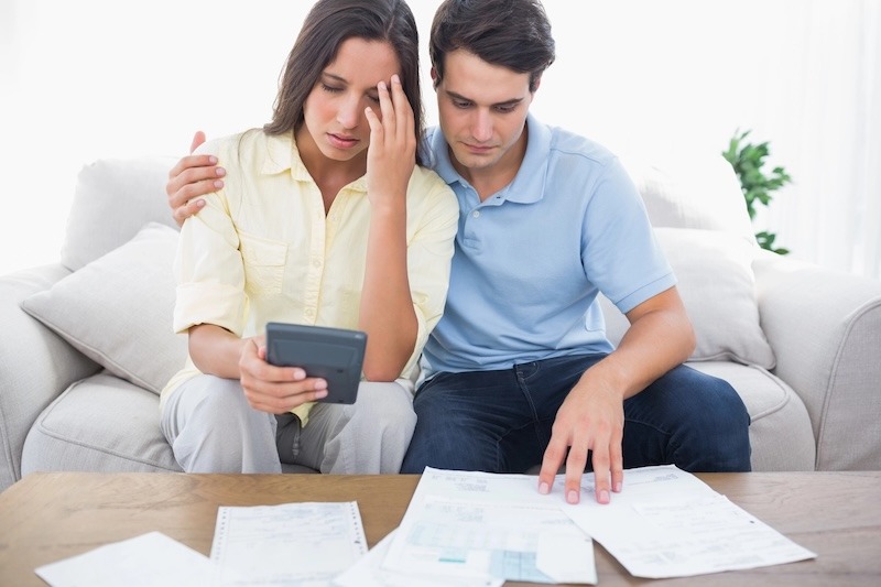 A worried couple looks over their bills in their living room